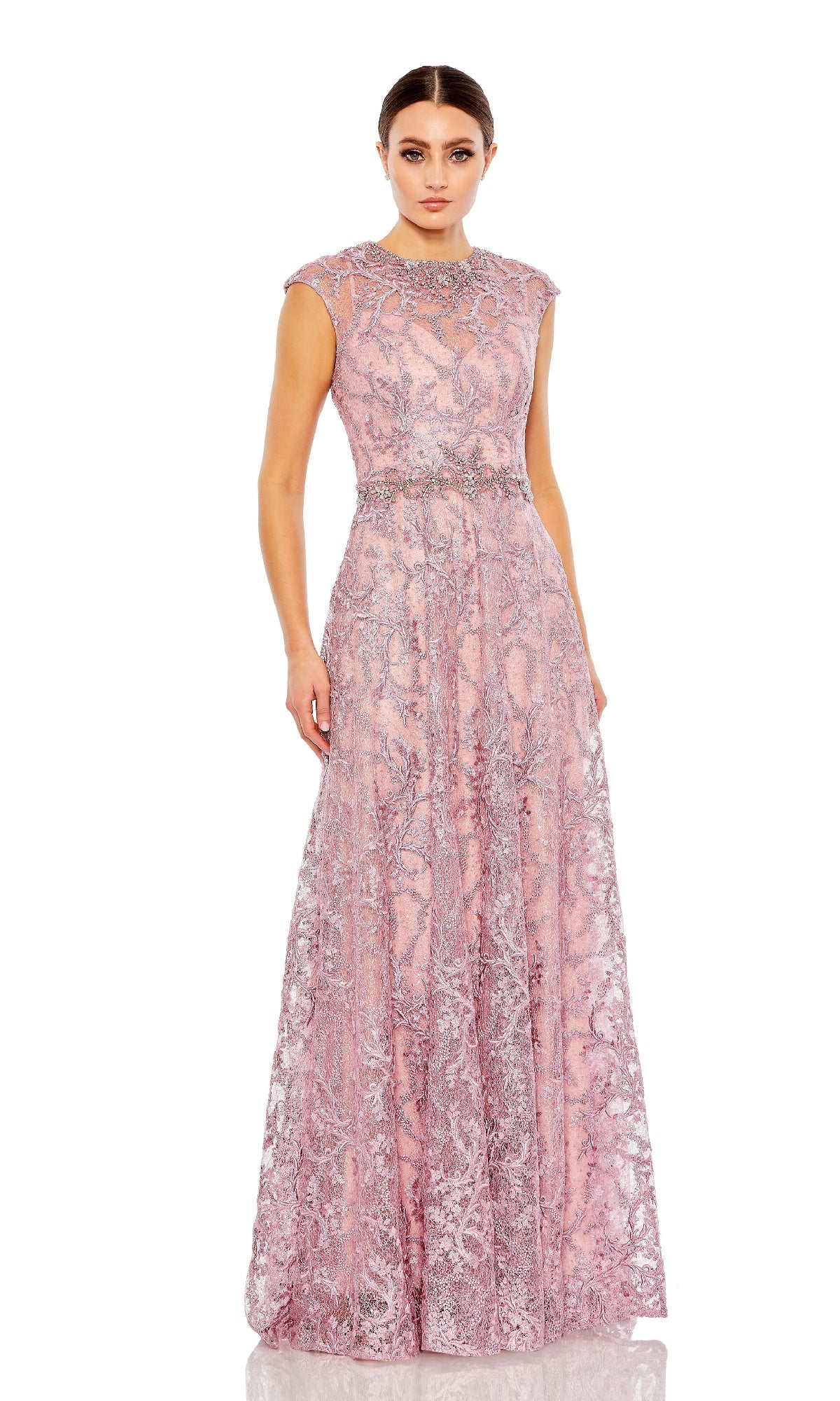 A woman in the Mac Duggal 79430 Long Beaded-Lace Formal Dress, a floor-length light pink gown with intricate lace and floral patterns, stands against a plain white background.